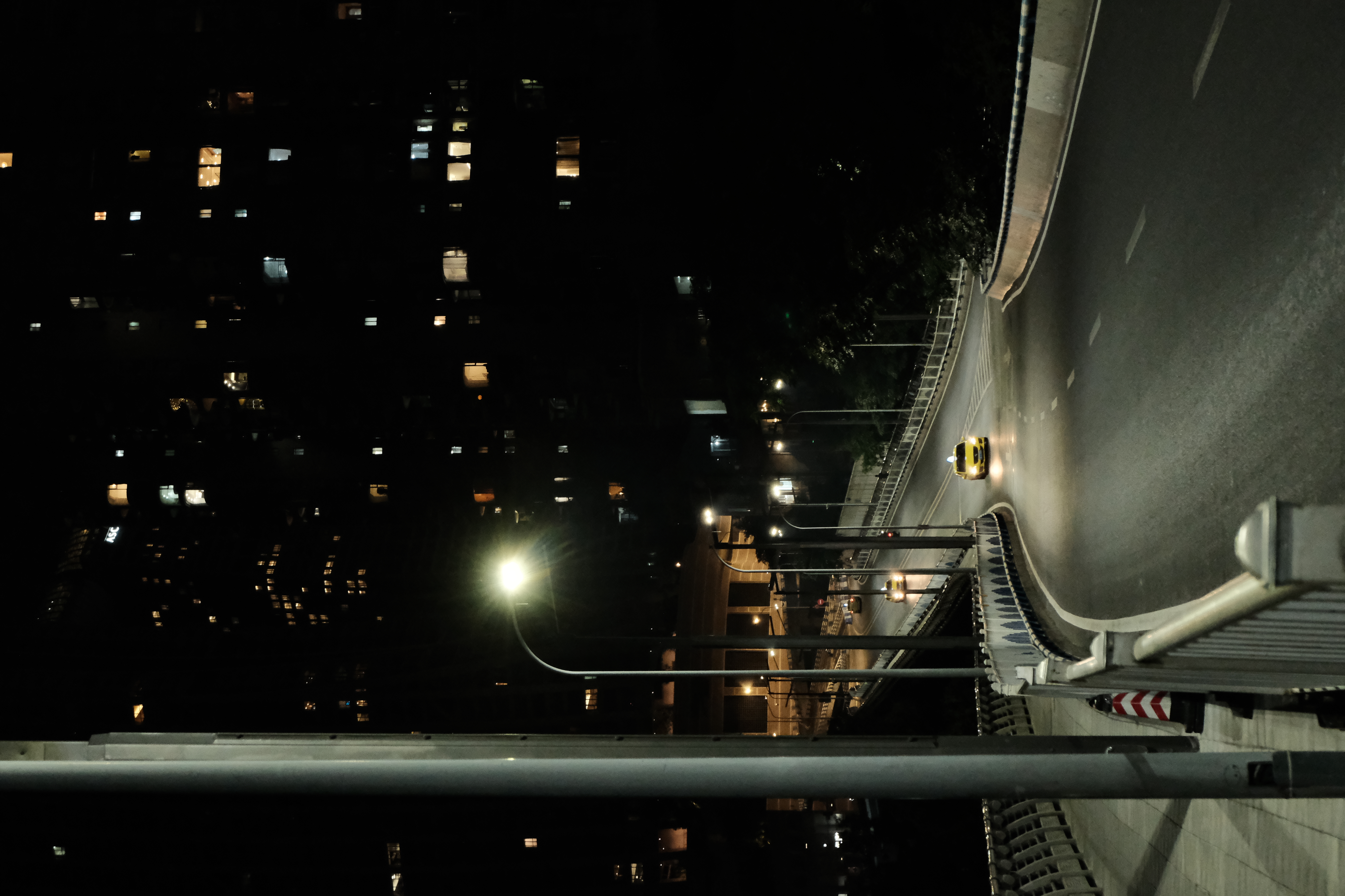 A lone taxi travelling along a curved city road at night